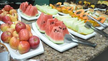 A buffet with various fruits including apples, watermelon, and papaya.