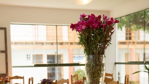 A breakfast buffet with various food items and drinks, a vase of flowers, and a view of the outside through large windows. - Inkarri Cusco (Cusco)