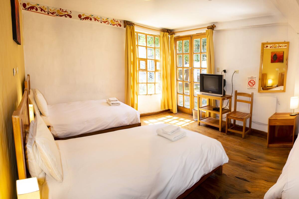 A hotel room with two beds, a television, a chair, and a small table.