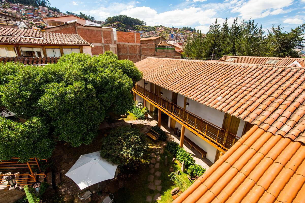 A courtyard with a tiled roof, a wooden bench, and a white umbrella.