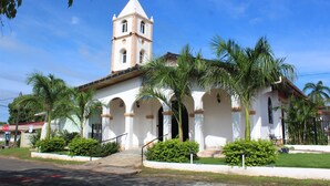 Una iglesia con campanario, ventanas en arco y fachada blanca.