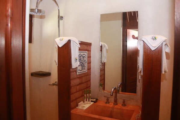 Un baño con tocador de madera, lavamanos, espejo y ducha.
