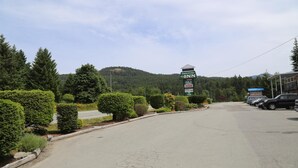 A road leading to a building with a sign indicating amenities like pool, sauna, and sushi. - Timberlodge RV & Campground (Port Alberni)