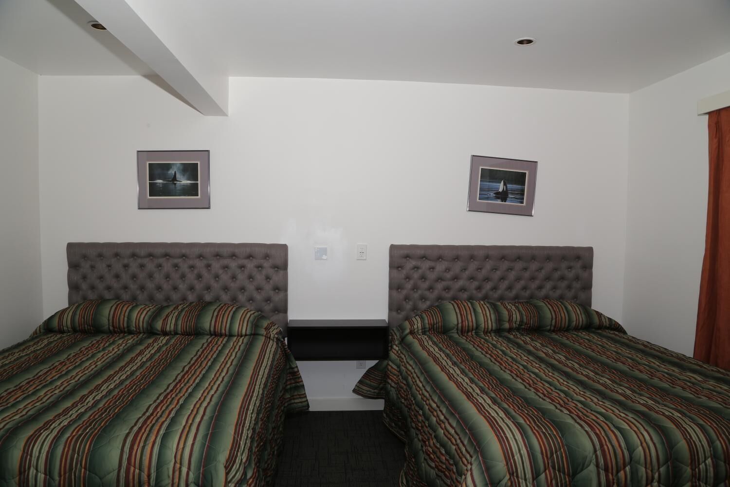 A twin room with two beds, each with striped bedding and tufted headboards.