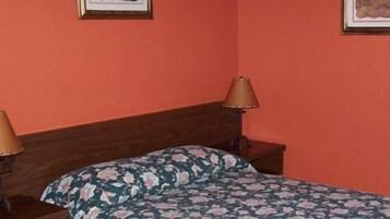 Un dormitorio con cabecera de madera, dos lámparas de noche y una colcha estampada con motivos florales.