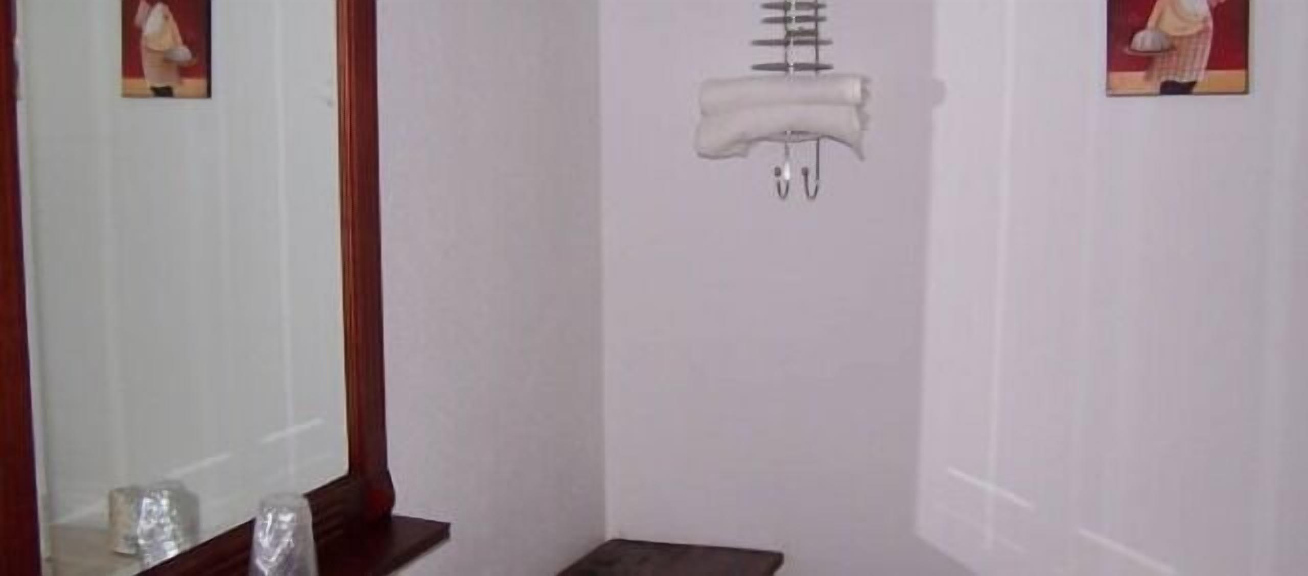 Une salle de bain avec un miroir, un porte-serviettes et une petite étagère sur laquelle sont posés quelques objets.