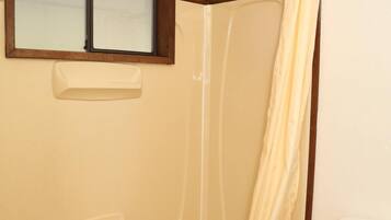 Ein Badezimmer mit einer Badewanne, einer Toilette und einem Fenster über der Wanne.