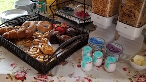 A breakfast buffet with various pastries, fruits, cereals, and dairy products. - Mulvehill Creek Wilderness Inn (Revelstoke)