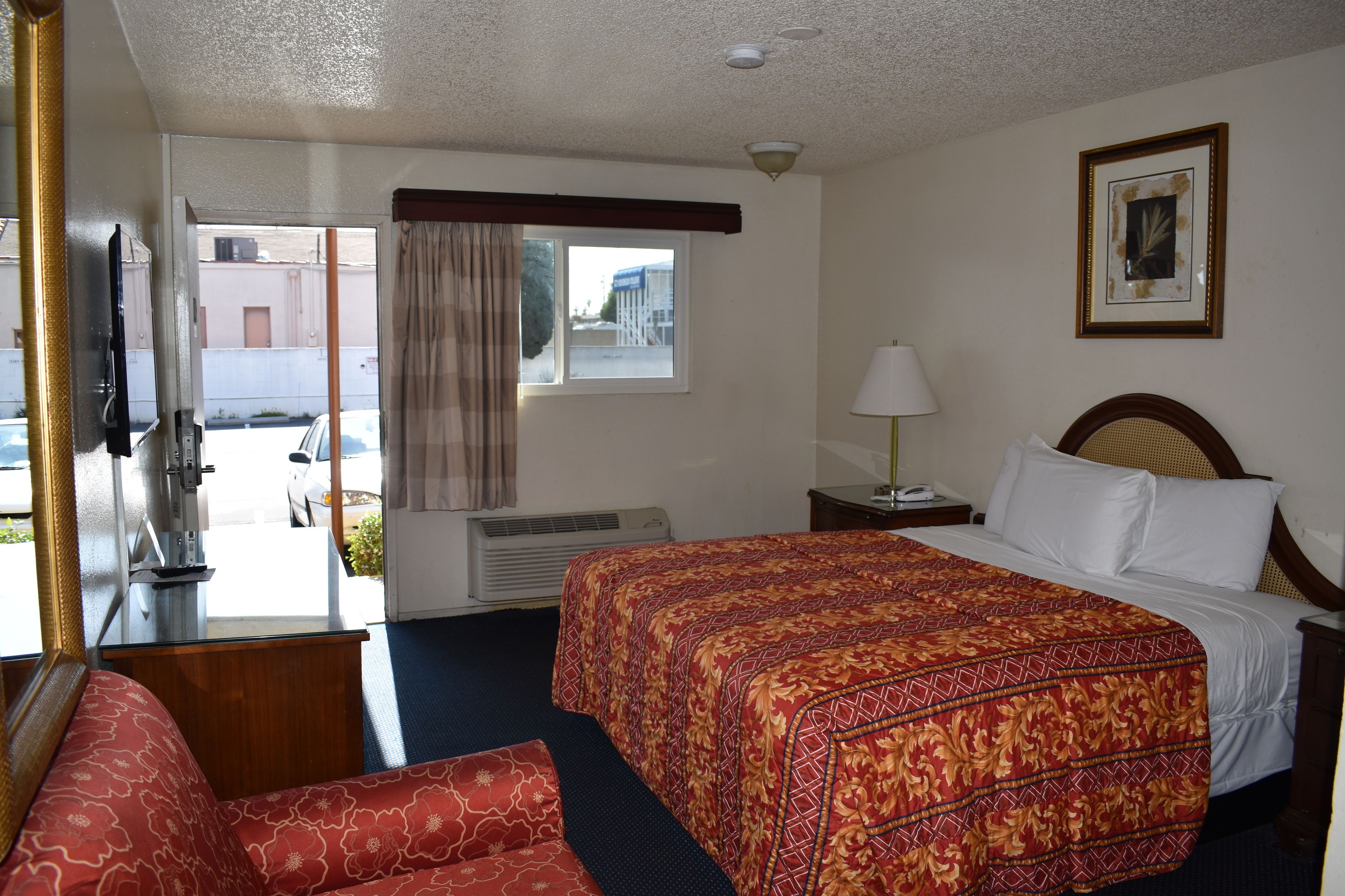 A hotel room with a bed, a desk, a chair, a window, and a wall-mounted TV.