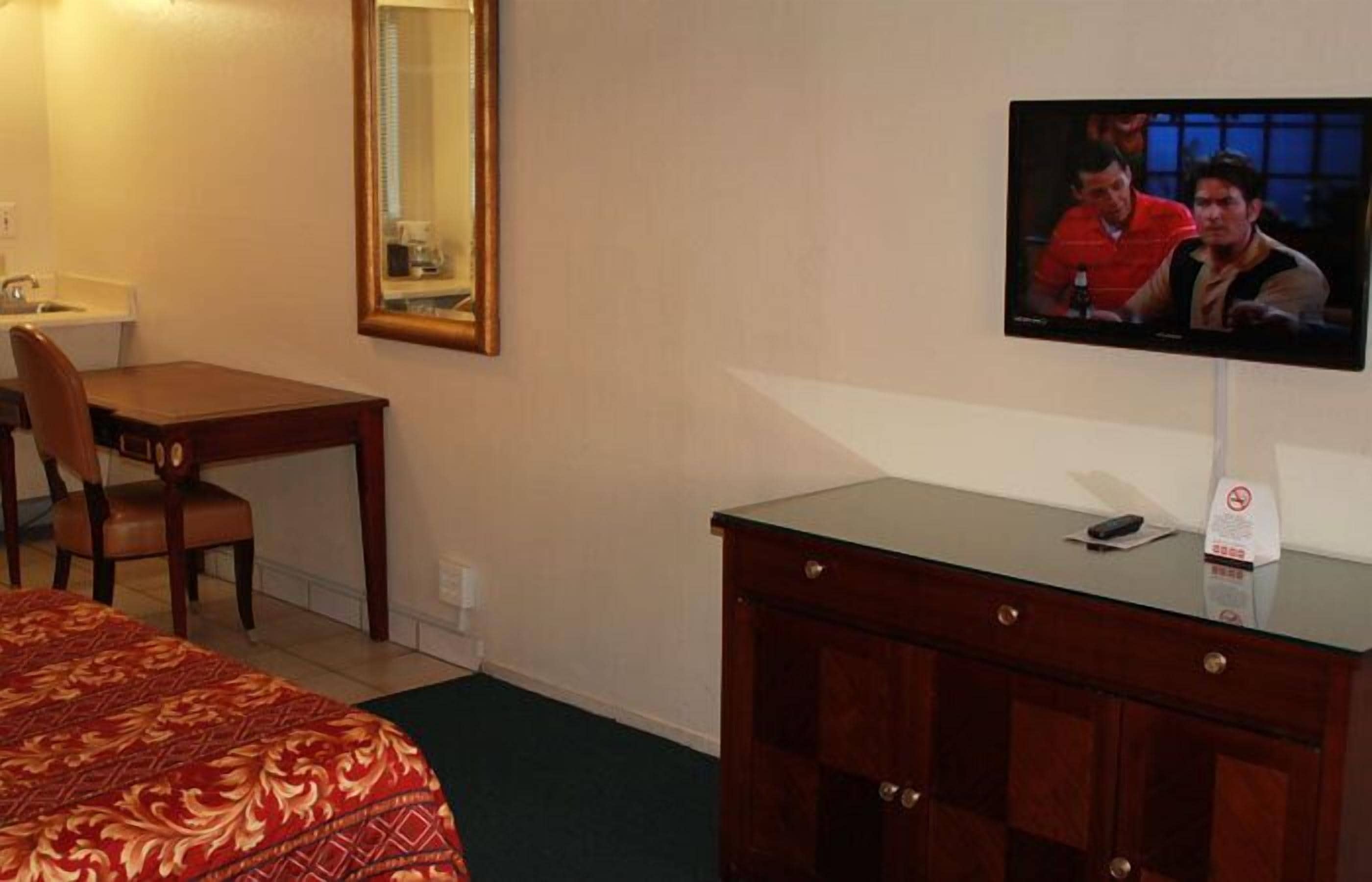 Une chambre d’hôtel équipée d’un lit, d’un bureau, d’une télévision et d’un miroir.