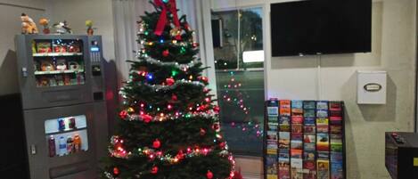 A living room with a decorated Christmas tree, a vending machine, and a DVD player.