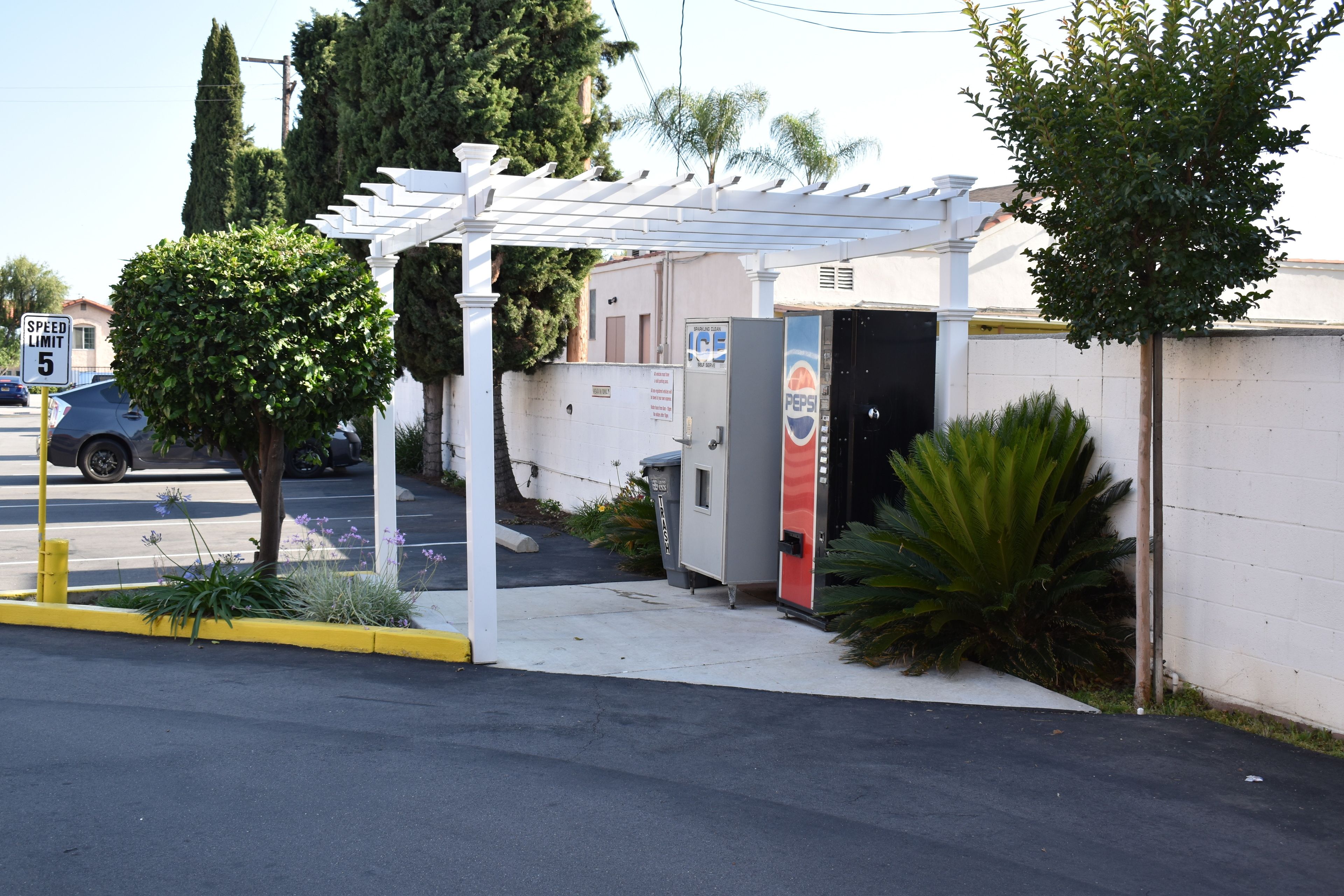 Un espace de stationnement avec un panneau indiquant la limite de vitesse, un distributeur automatique et une structure abritée.