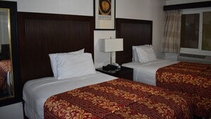 Una habitación de hotel con dos camas, una mesita de noche, una lámpara y un cuadro en la pared.
