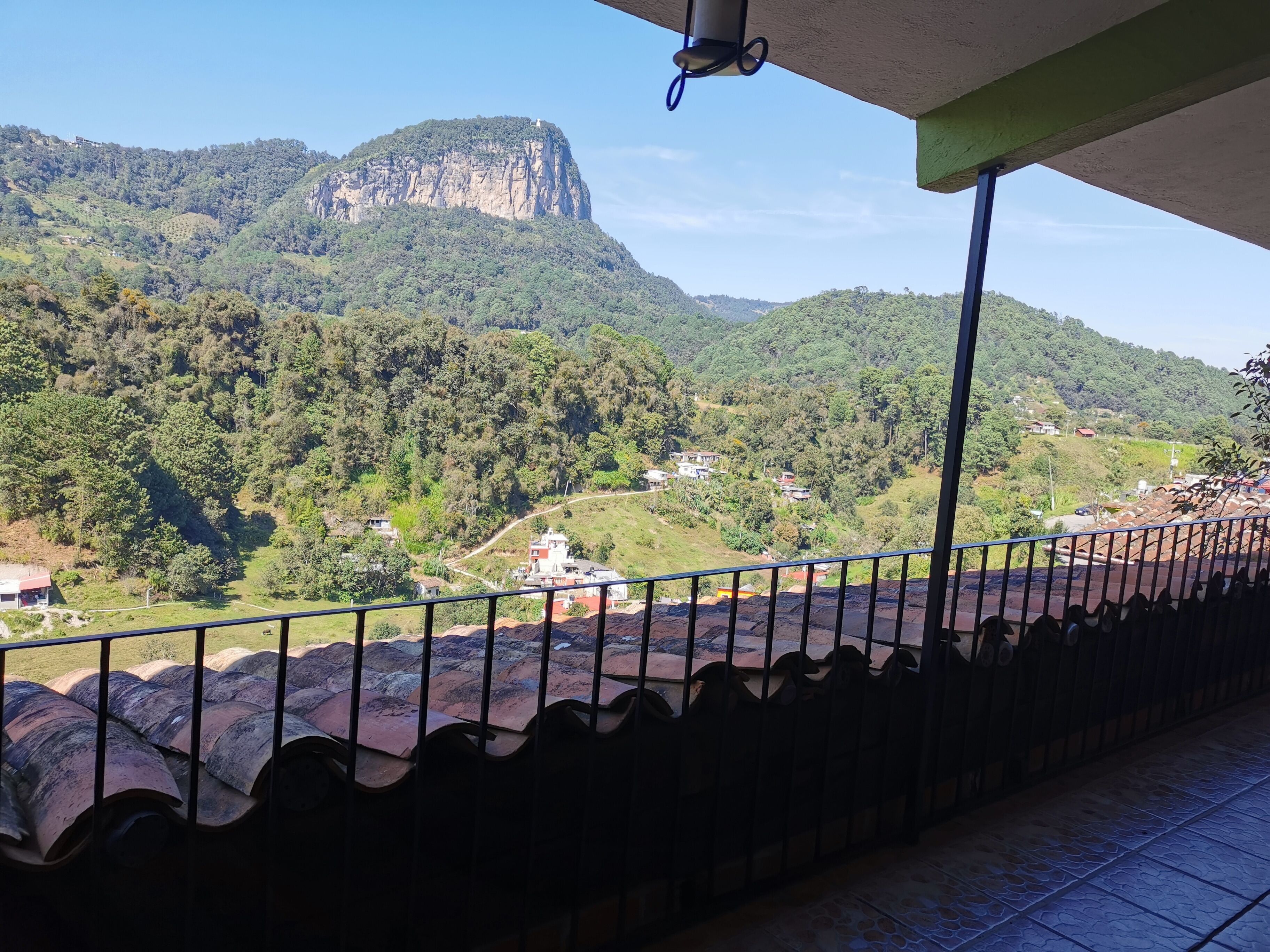 A balcony with a view of a mountainous landscape and a distant building.