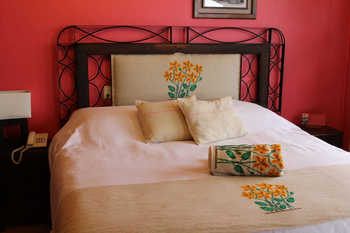 Ein Bett mit Kopfteil, Kissen und einer Decke mit Blumenstickerei.