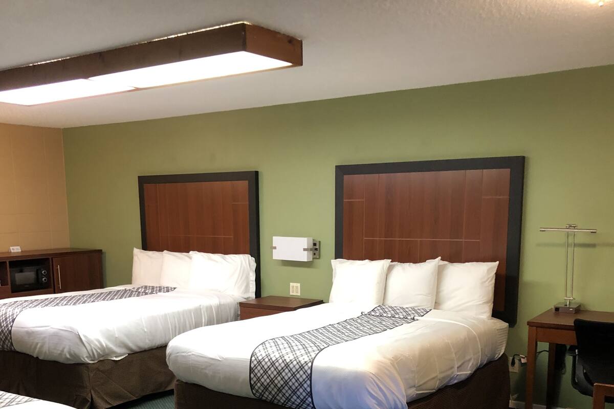 A hotel room with two beds, a desk, a chair, and a nightstand.