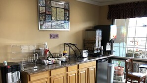 A kitchen with wooden cabinets, a stainless steel refrigerator, a coffee maker, and a window with a view. - Knight's Inn Motel (Grants Pass)