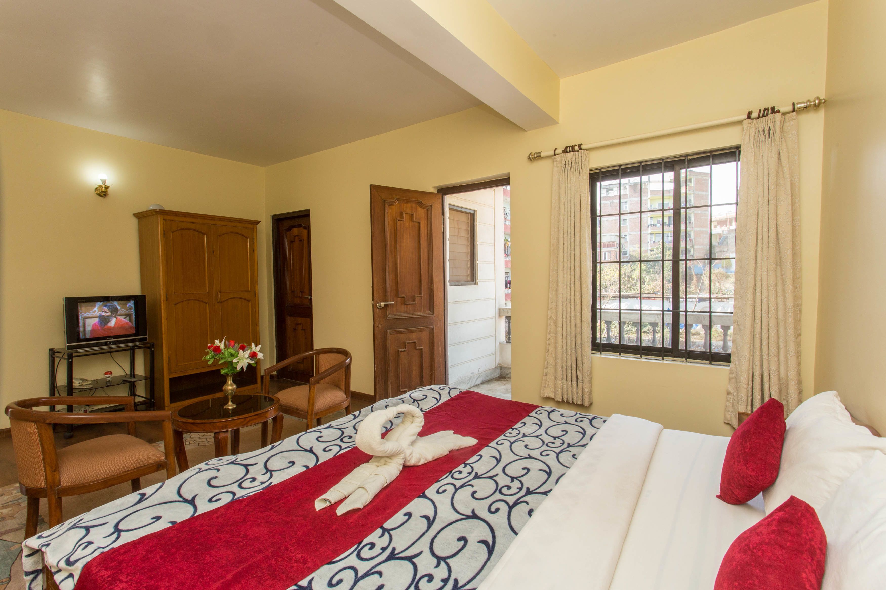 Una habitación de hotel con cama, televisión, escritorio con silla y ventana con cortinas.