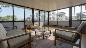A spacious room with large windows, a round glass table, and four upholstered chairs. - Hotel Norbu Sangpo (Kathmandu)