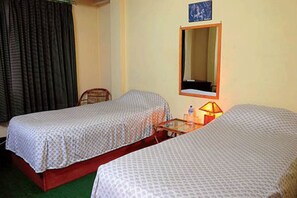 A room with two single beds, a chair, a table with a lamp, and a mirror on the wall. - Kirtipur Hillside Hotel and Resort (Kirtipur)