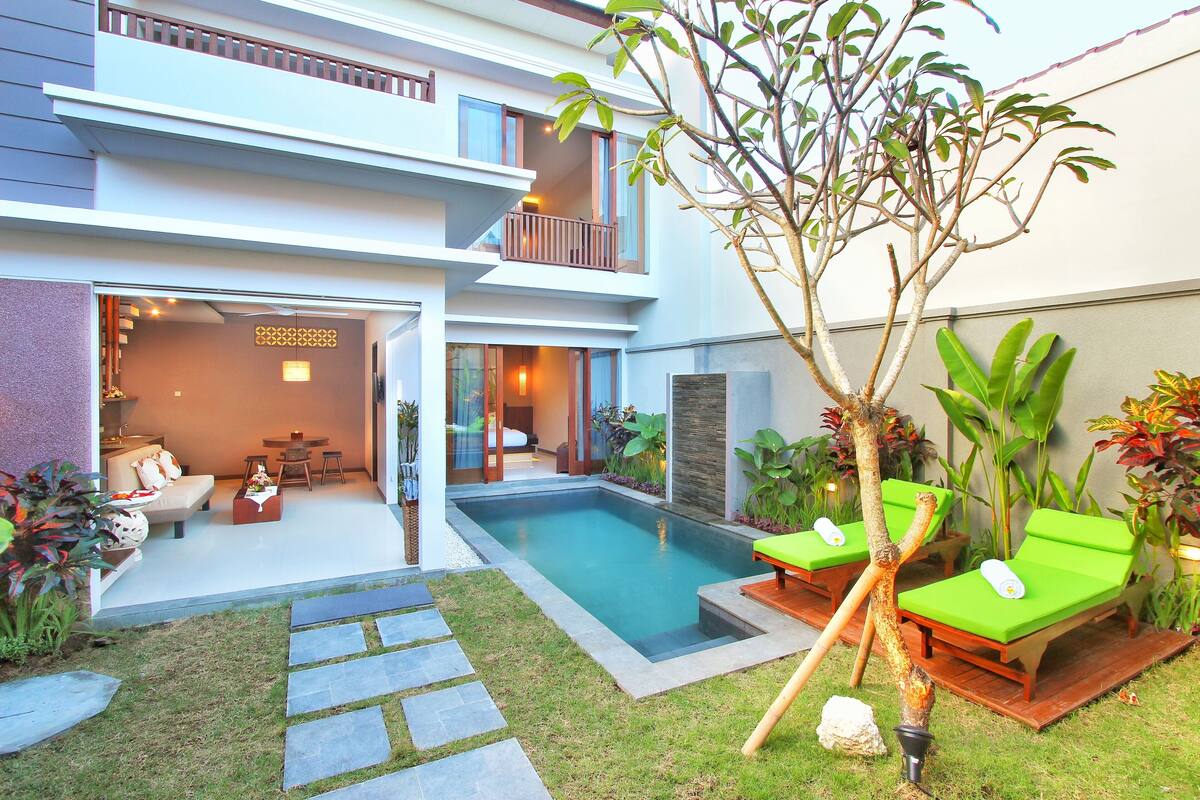 Una casa moderna de dos pisos con piscina, mobiliario exterior y un jardín bien cuidado.