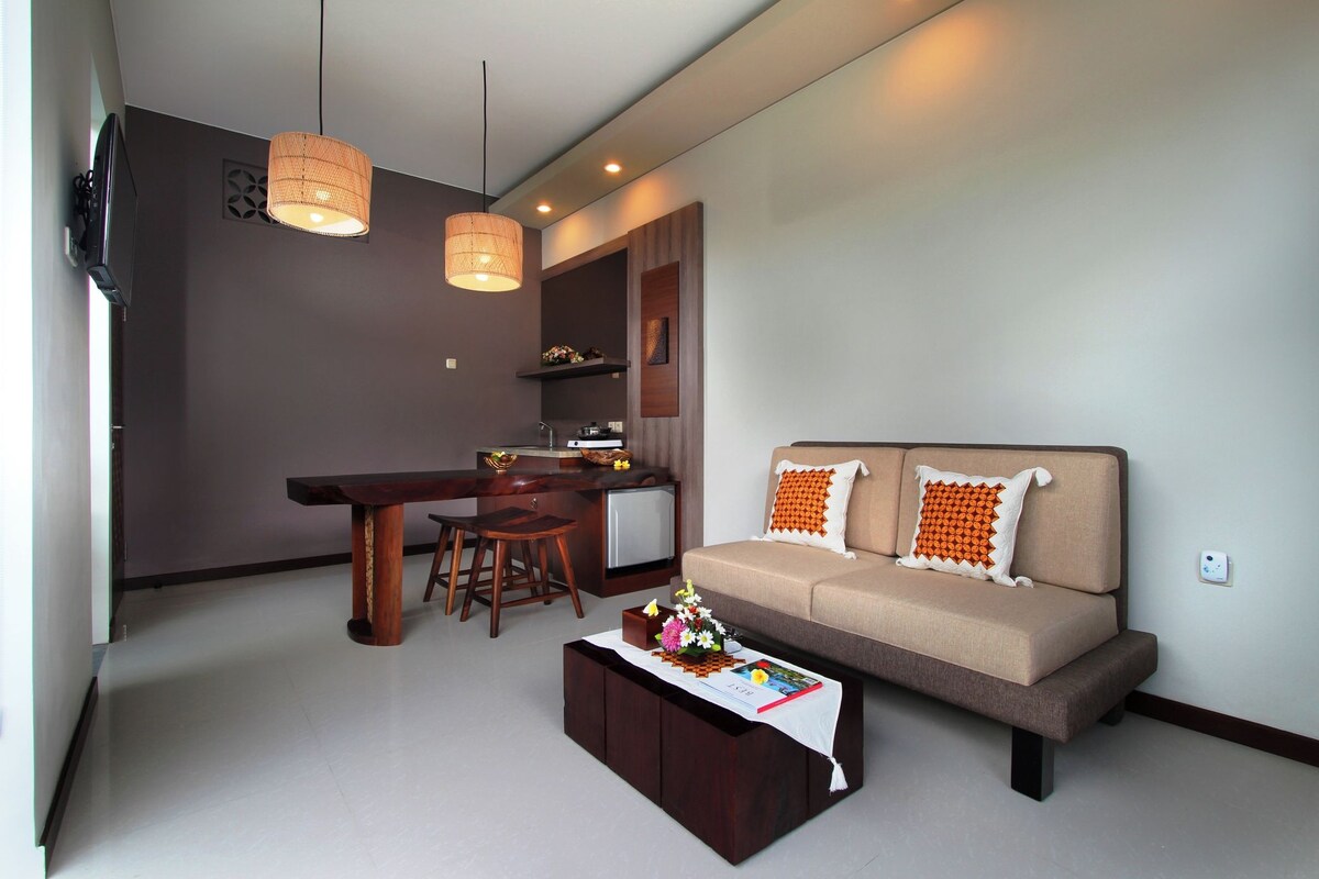 A modern living room with a sofa, coffee table, dining area, and kitchen.