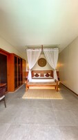A bedroom with a four-poster bed, a wooden headboard, and a woven wall hanging.