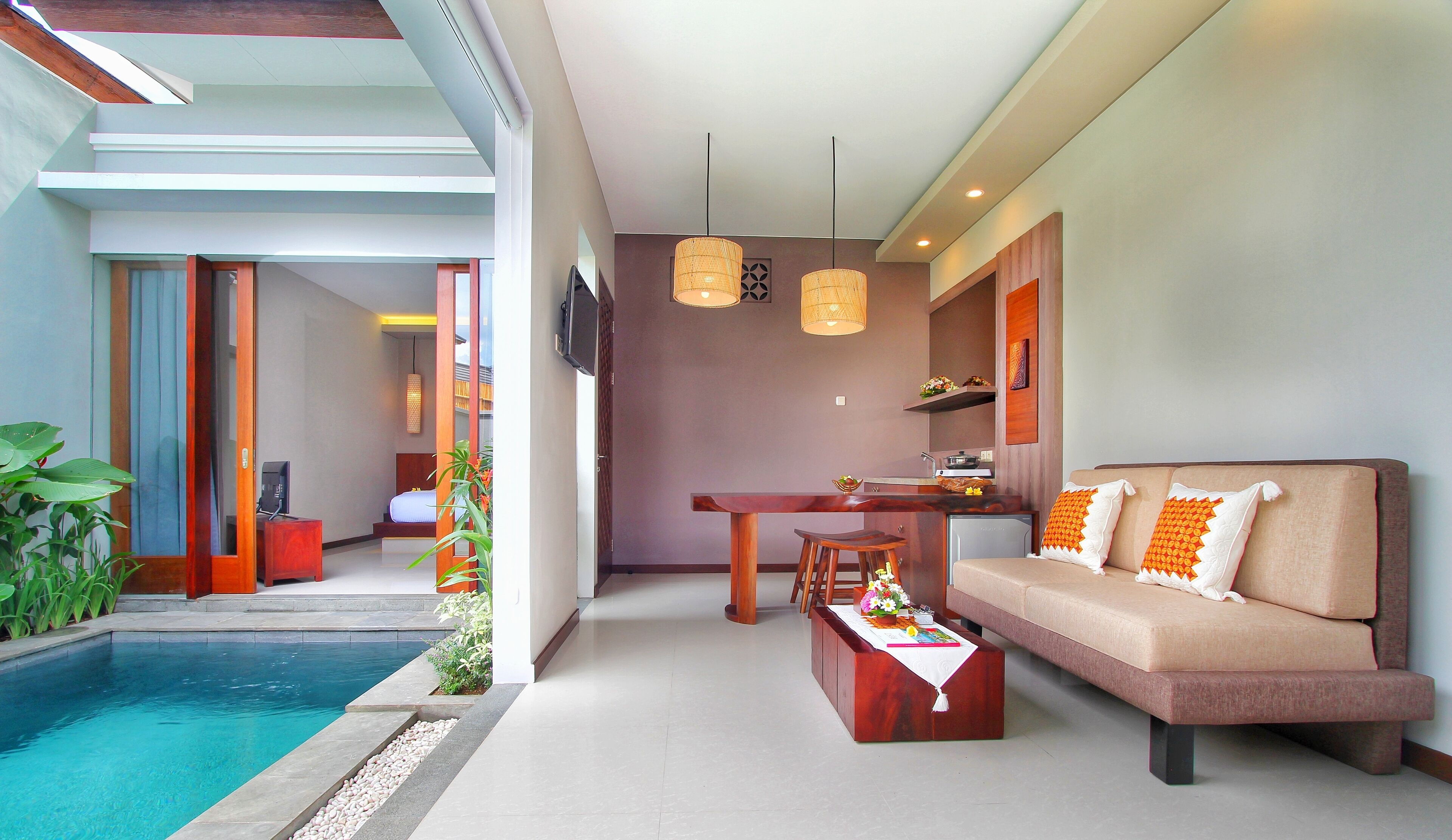 A modern living room with a pool, a sofa, a dining table, and a kitchen area.