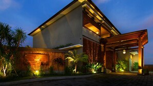 Un hotel moderno con un gran cartel, una entrada cubierta y jardines bien cuidados.