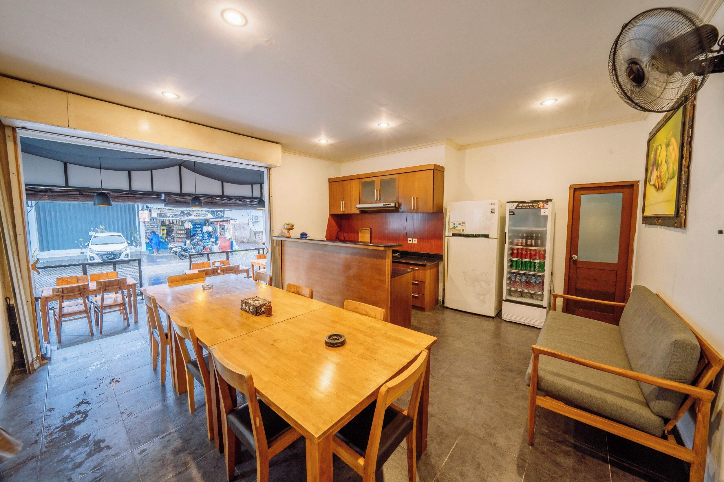 Une cuisine compacte avec des meubles en bois, une table à manger avec des chaises, un canapé et un réfrigérateur.