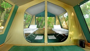 A tent with two beds, a table, and a trash can. - The Yala Camping (Tissamaharama)