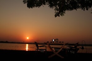 A table and chairs set up by a lakeside at sunset. - The Yala Camping (Tissamaharama)