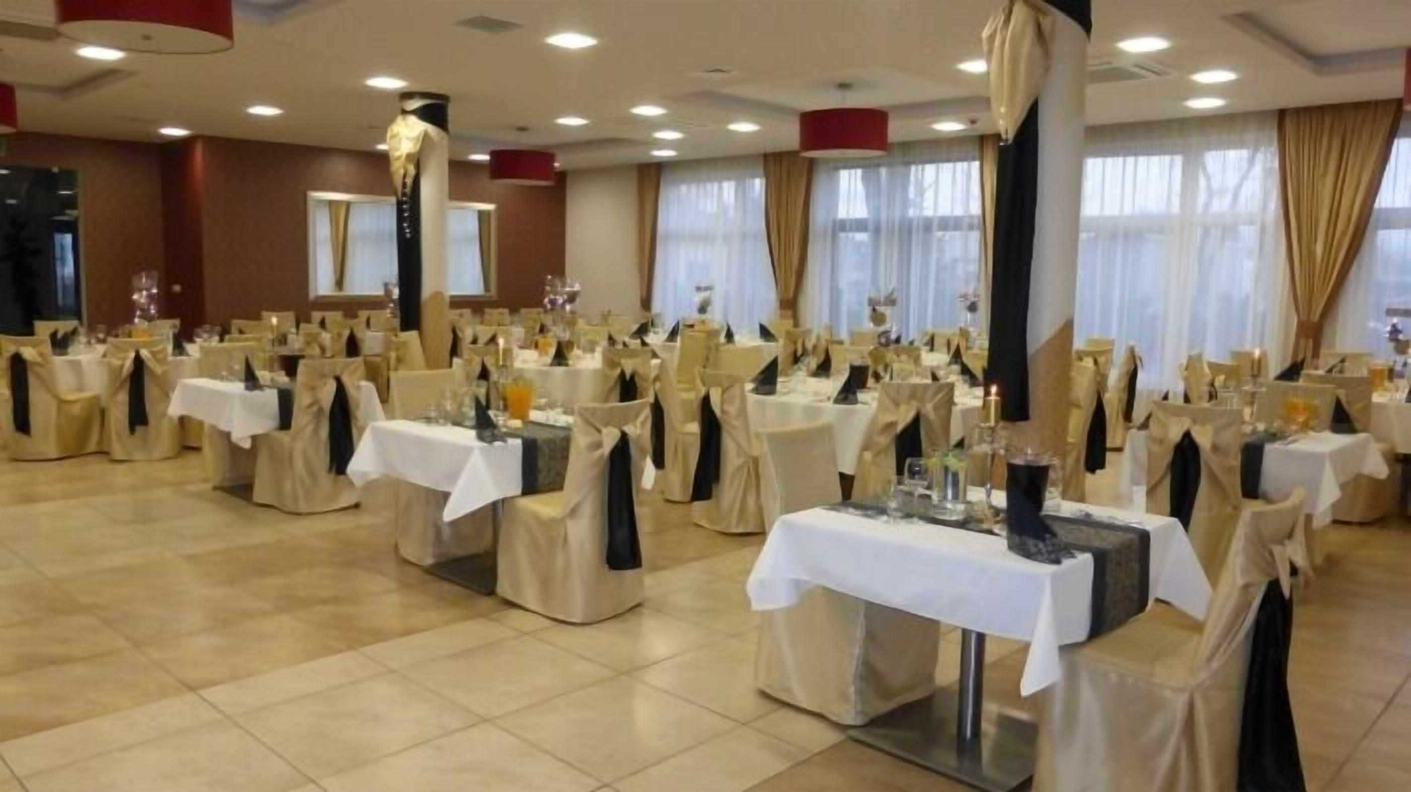 Un salón de banquetes con mesas redondas, sillas y un escenario.