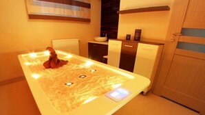 Un spa moderno con un baño de piedras calientes, un lavamanos pequeño y un armario de madera.