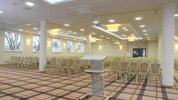 A conference room with rows of chairs, a podium, and a checkered carpet.