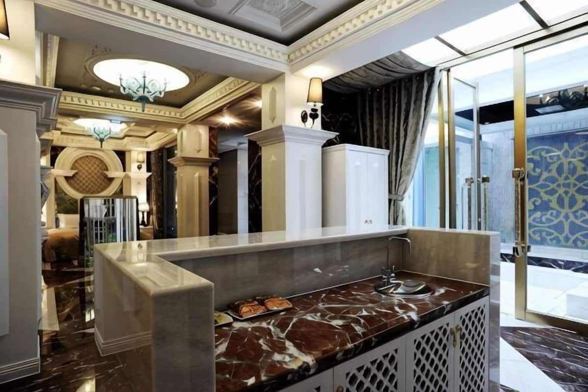 A lobby with a marble reception desk, a chandelier, and a patterned wall.