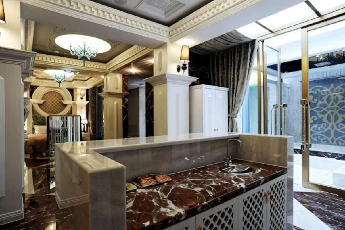 A lobby with a marble reception desk, a chandelier, and a patterned wall.