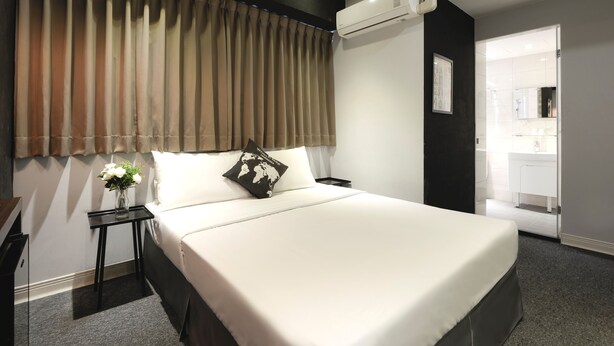 A modern hotel room with a large bed, a nightstand, a vase with flowers, and an air conditioning unit. - Taichung Box Design Hotel (Taichung)