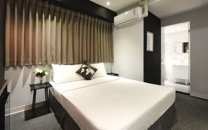 Een moderne hotelkamer met een groot bed, een nachtkastje, een vaas met bloemen en een airconditioner.