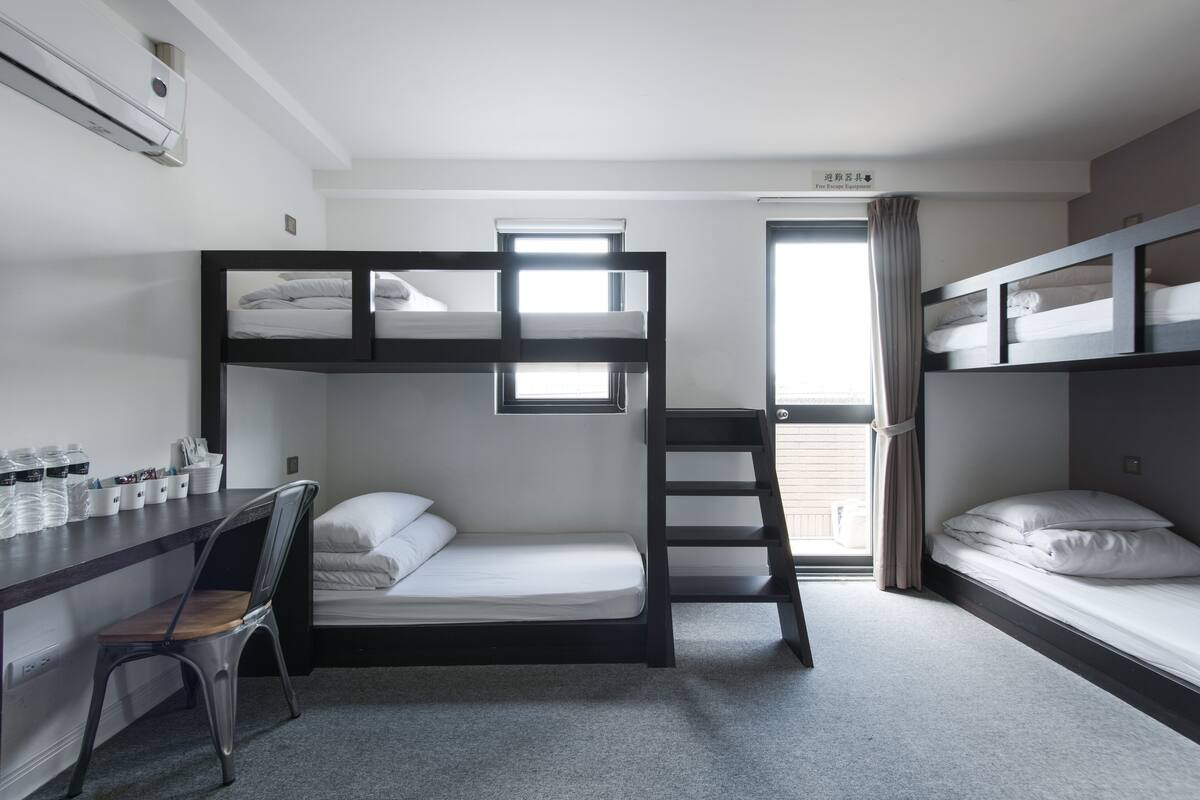 Quarto com beliche, escrivaninha, cadeira e escada.