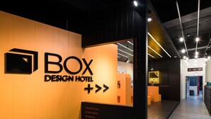A modern hotel entrance with a prominent 'BOX DESIGN HOTEL' sign, a reception desk, and directional arrows on the floor. - Taichung Box Design Hotel (Taichung)