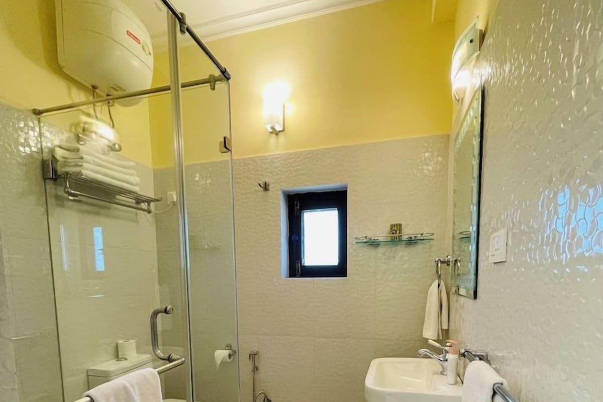 Ein Badezimmer mit Duschkabine aus Glas, Waschbecken und Toilette.