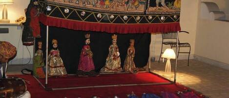 Una habitación con alfombra roja, un fondo negro con obras de arte coloridas y una fila de maniquíes vestidos con trajes tradicionales.