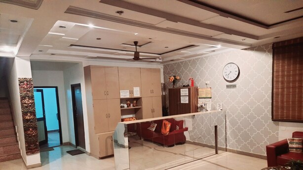 A modern interior with a reception desk, a clock, and a ceiling fan. - Hotel Aicon Palace (Agra)