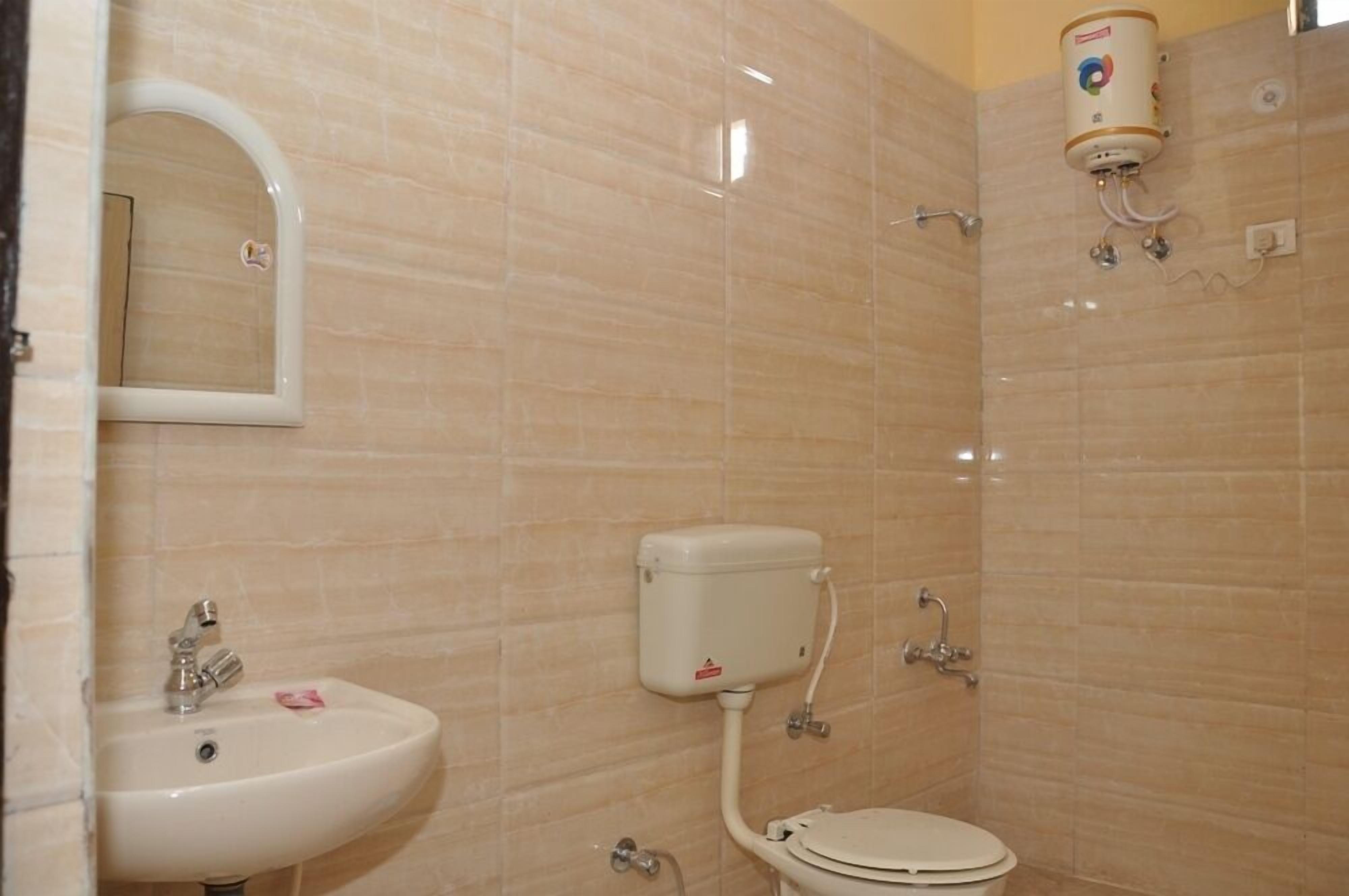 A bathroom with a sink, toilet, and a shower with a water heater.