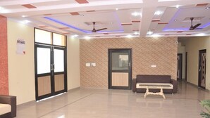 A spacious lobby with a modern ceiling design, a reception desk, and a seating area. - Hotel Aicon Palace (Agra)