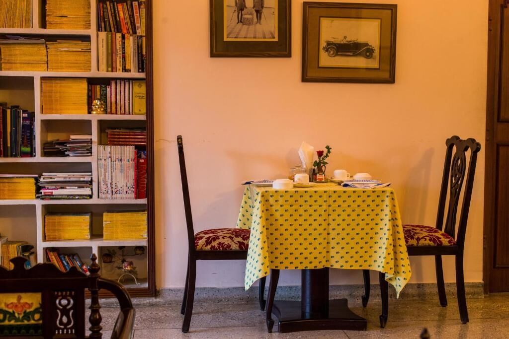 Un comedor con una mesa preparada para dos personas, una estantería llena de libros y cuadros en la pared.