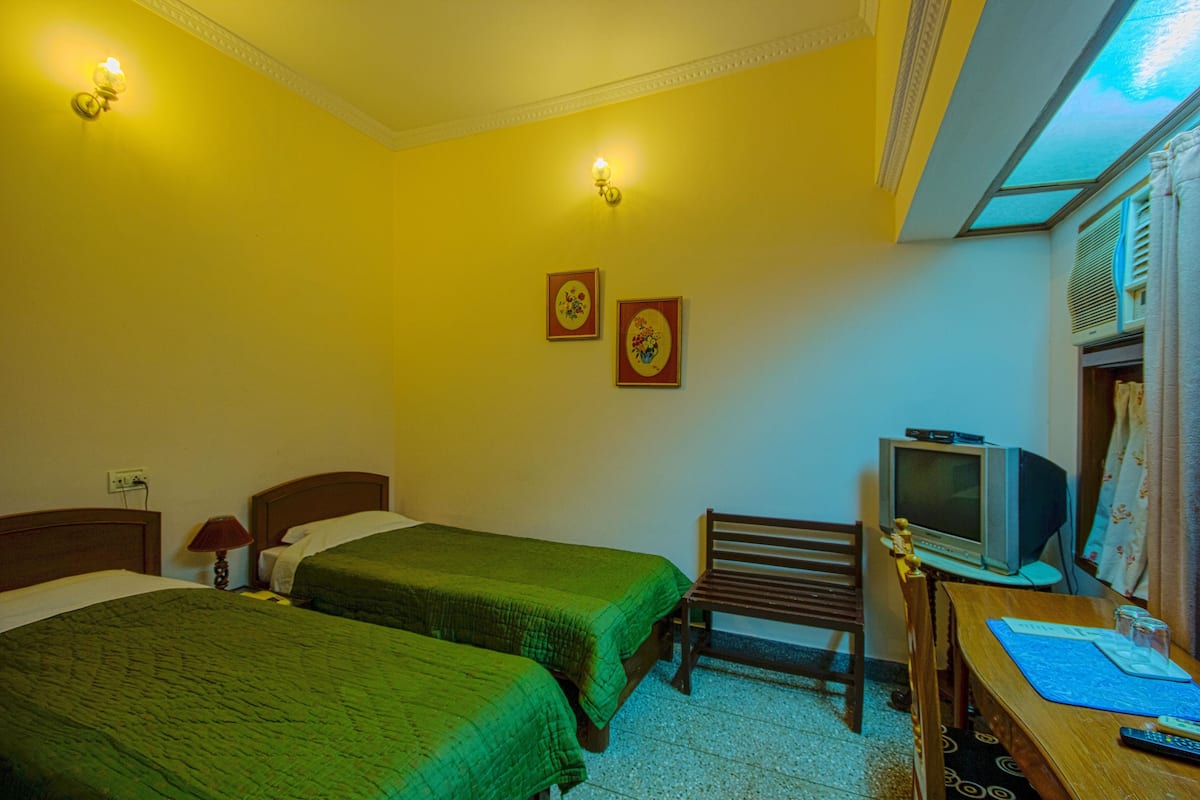 Une chambre avec deux lits, un bureau avec une télévision et une chaise.