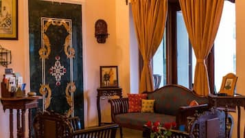 Una habitación tradicional con sofá, sillas, una mesita y un adorno en la pared.
