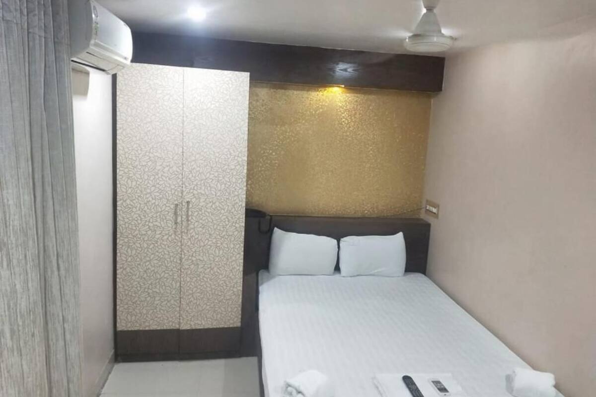 A small, compact hotel room with a bed, a wardrobe, and a ceiling fan.